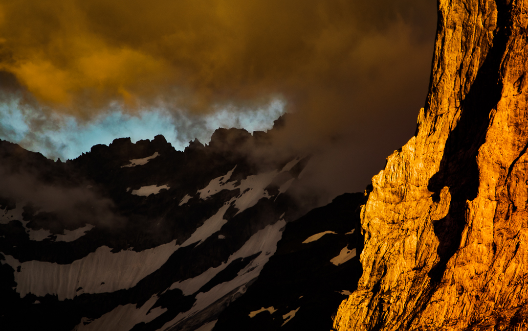 Dramatic Mountain Mood - Photograph made close to Engelberg / Switzerland, during summer. The sun was already close to the horizon, and peeked through the clouds for a moment, lighting up parts of the mountains and clouds in a warm, still a little eerie light, creating a very special scene. 